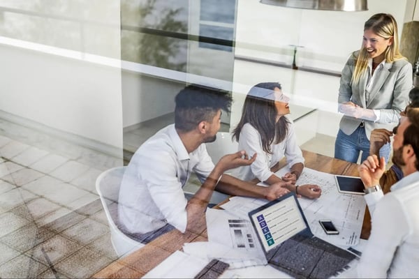 Team working together around a desk, smiling, using the ADKAR Model